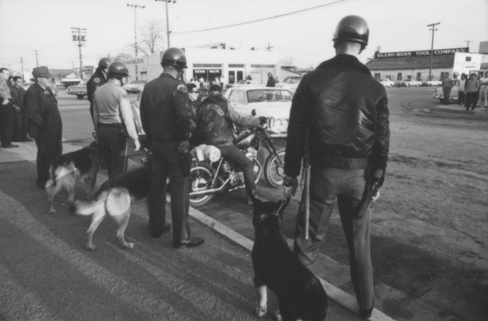  Officers with dogs stop to look at members of the Hells Angels outside the Blackboard Cafe