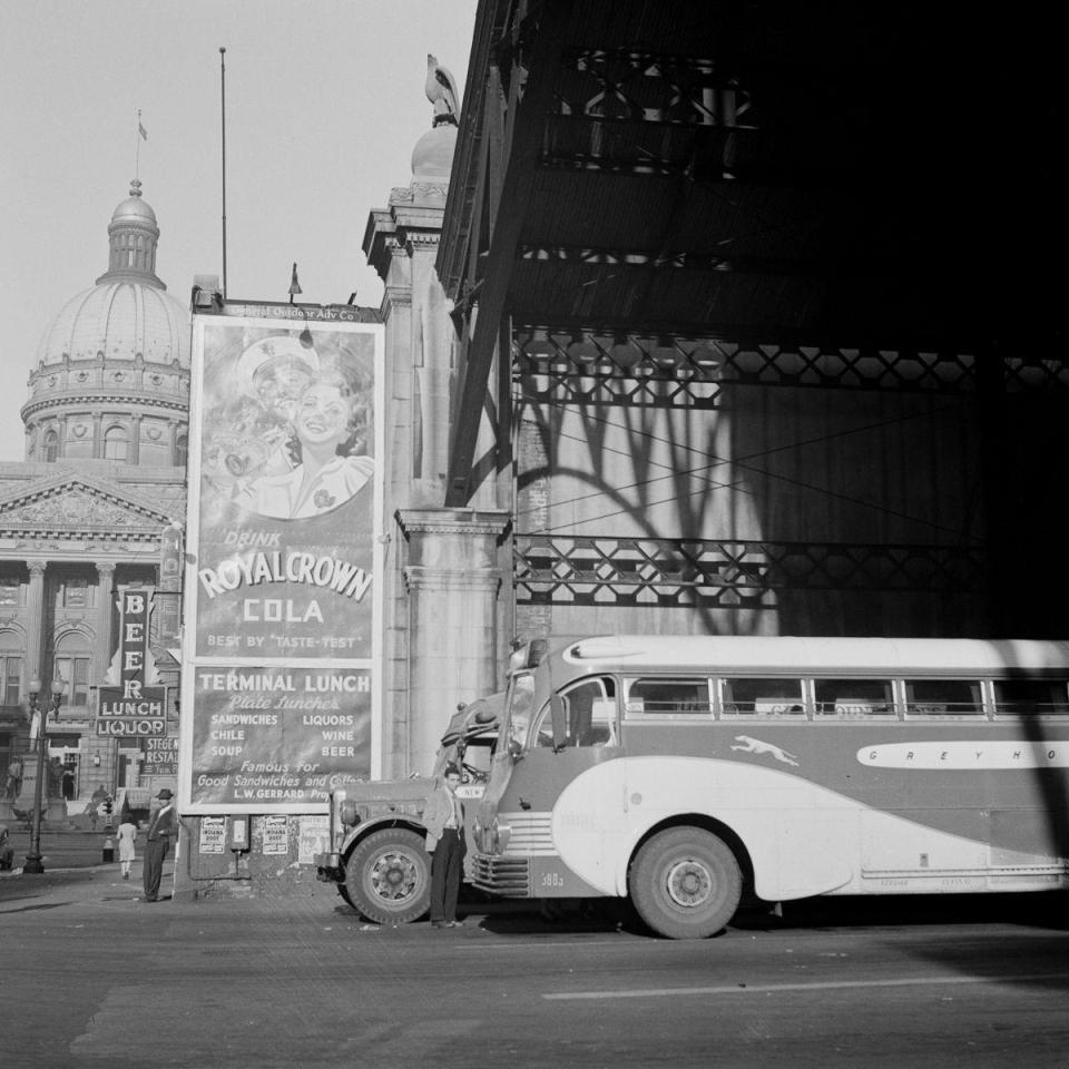  A vintage bus pulls up next to an advert for American cola, outside the coach terminal