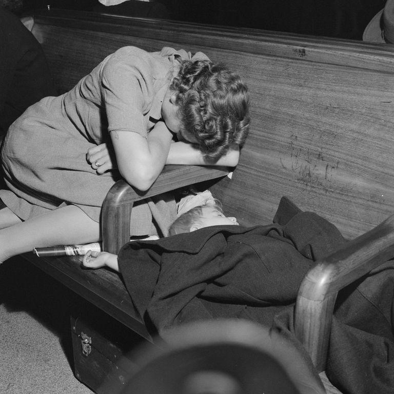  A female passenger sleeps next to her young child as they wait for a coach