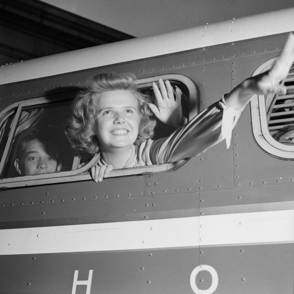  A young woman waves goodbye from inside a Greyhound coach