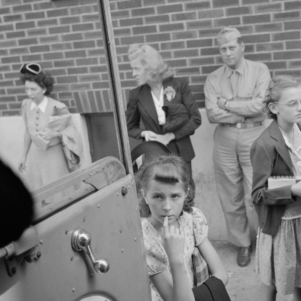  A young girl stares up into the bus from the pavement