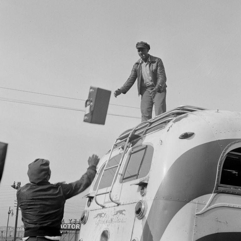  The bus driver throws luggage down from the roof of the vehicle