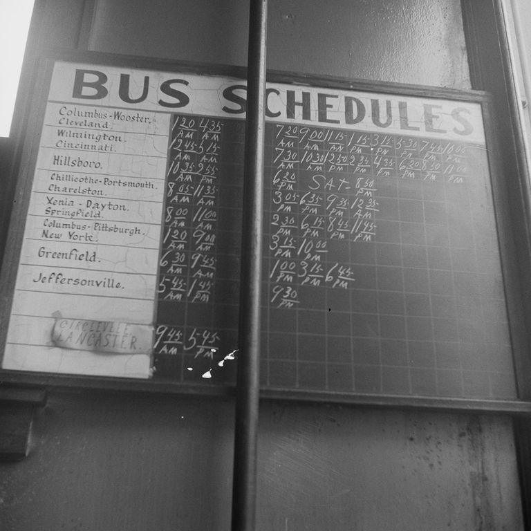  An old bus schedule sign shows the timings of each bus marked in chalk