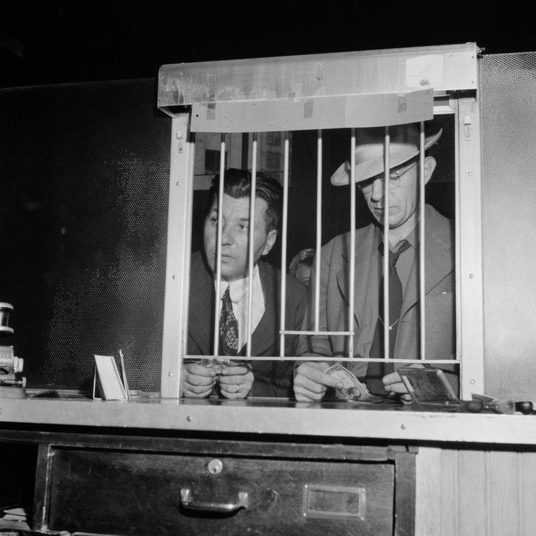  Two men queue for tickets at a coach station booth