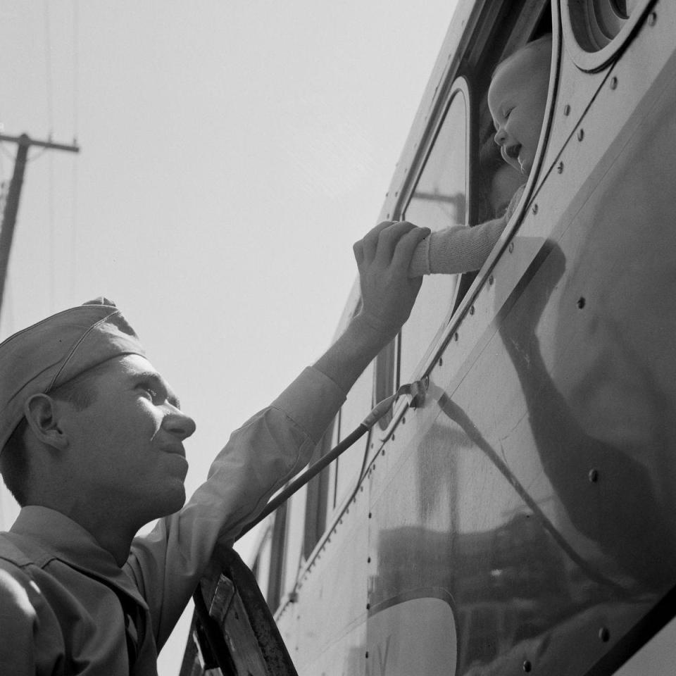  An army man waves goodbye to his young child from the pavement