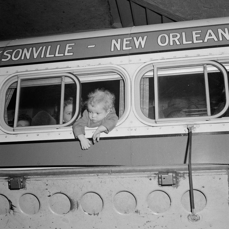  A baby hangs out of the bus window as the bus prepares to leave the station