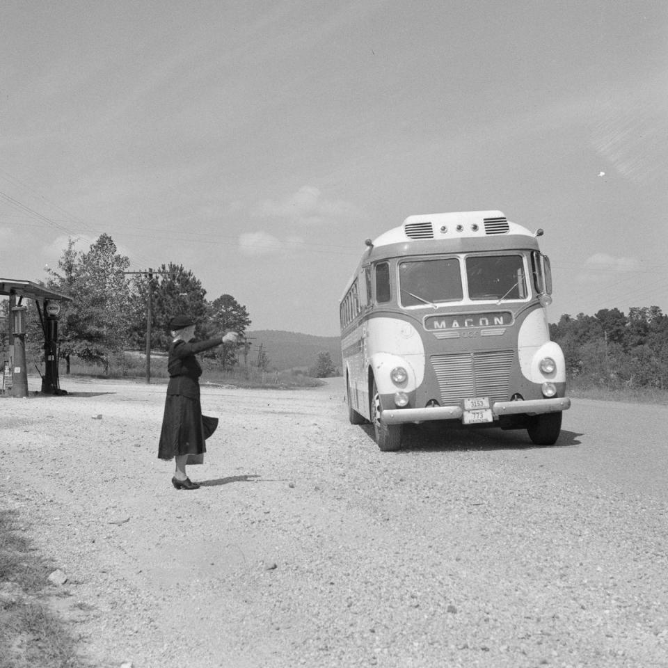  A  woman hails a passing coach from the side of the road