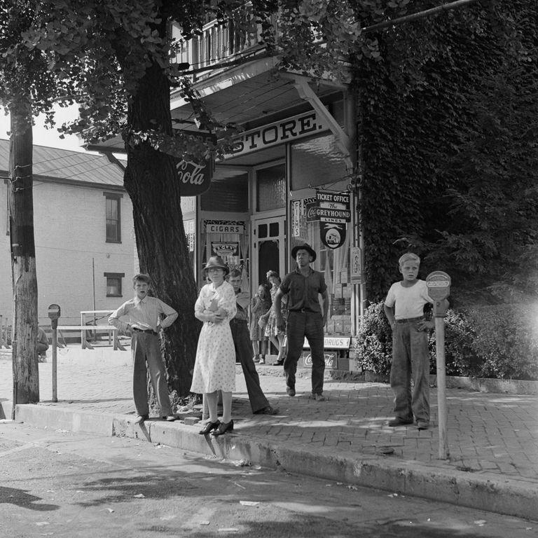  Locals are pictured watching the bus go by next to the town store