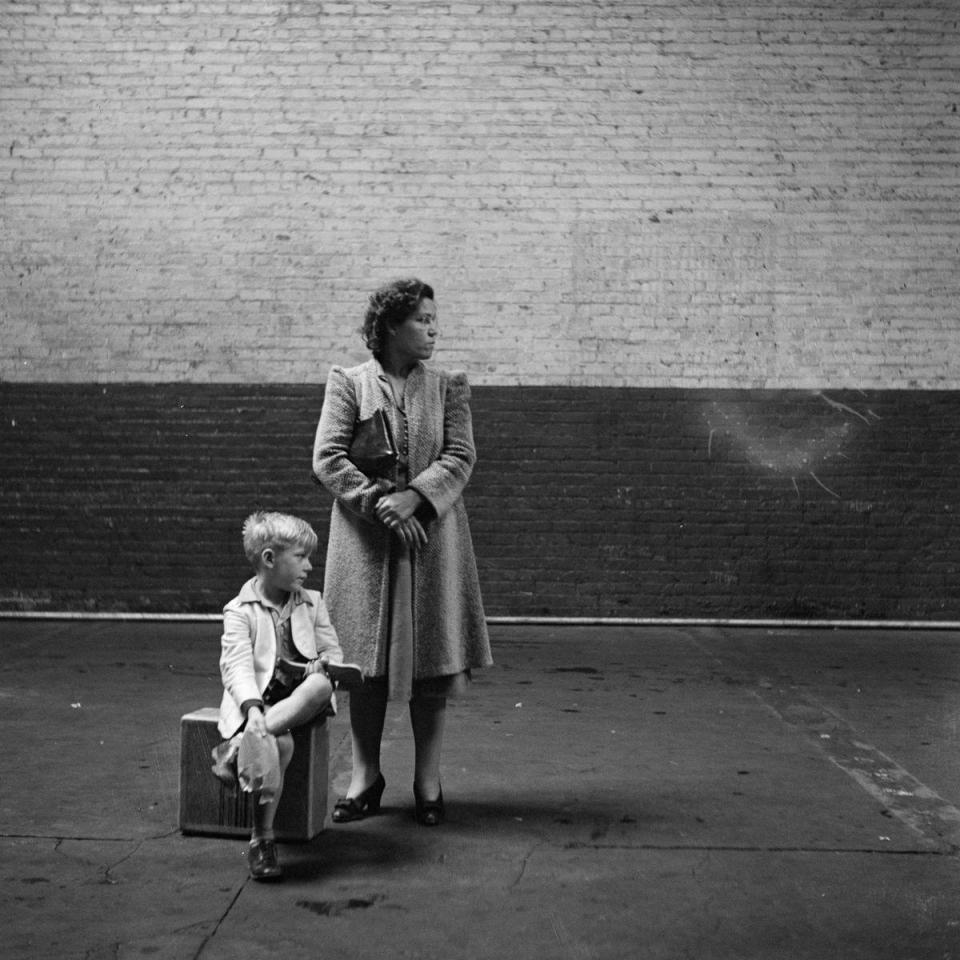  A woman and a young boy wait on an empty bus concourse for their ride