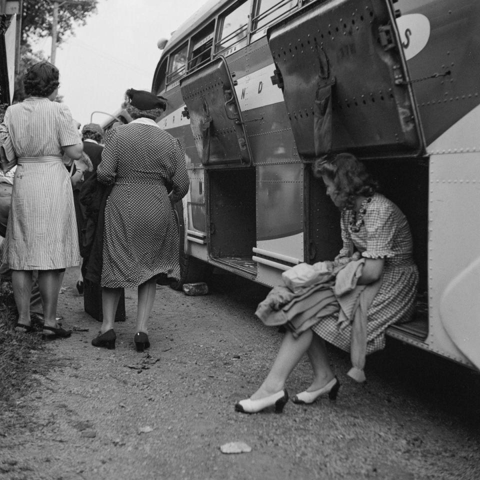  A female passenger waits in the luggage hold of a Greyhound bus as people board