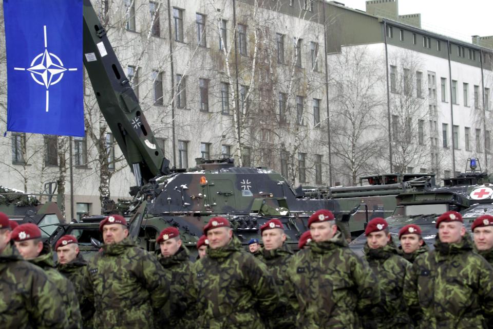  Dutch soldiers take part in a parade while the NATO banner hangs above them