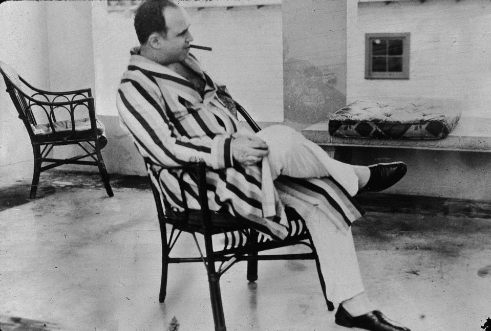  Al Capone relaxes in his holiday home in Florida wearing a striped dressing gown and smoking a cigar