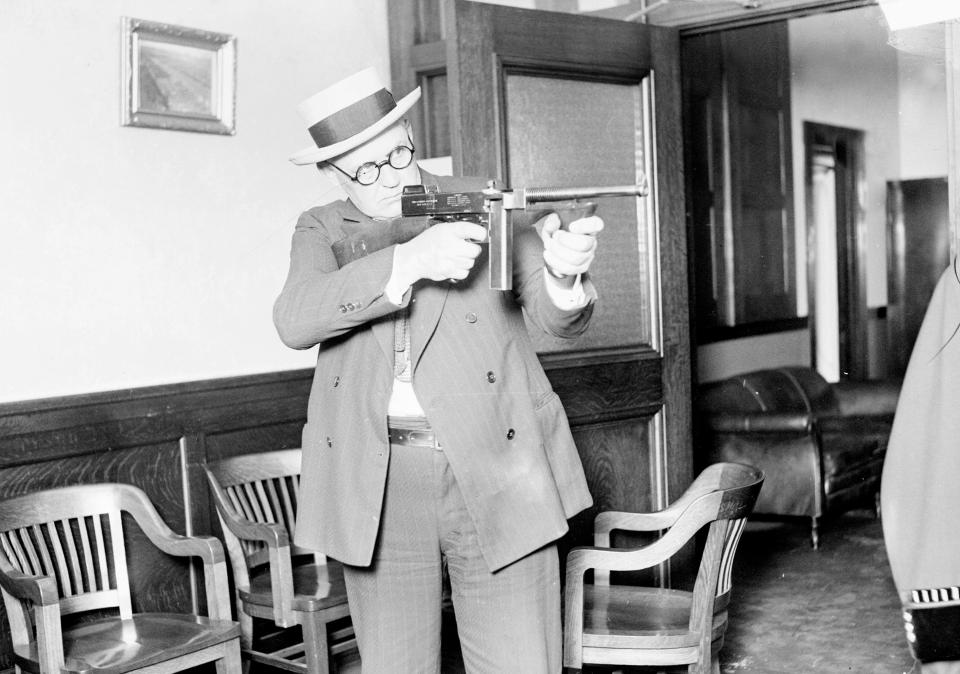  A police lieutenant aims a Thompson machine gun, was a popular weapon among gangsters