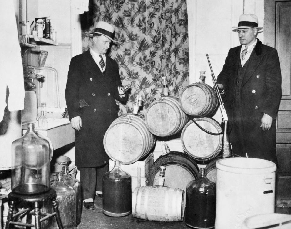  Police officers look over distilling equipment and guns confiscated during a Prohibition raid