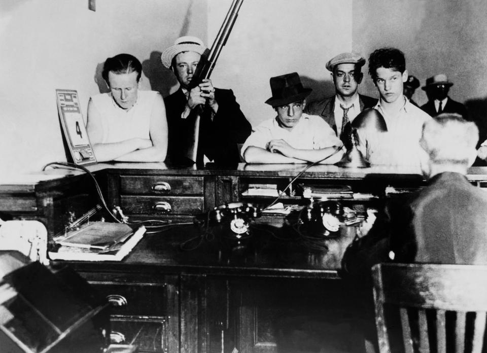  Gangsters stand with their weapons after being brought into a police station in New York in 1931