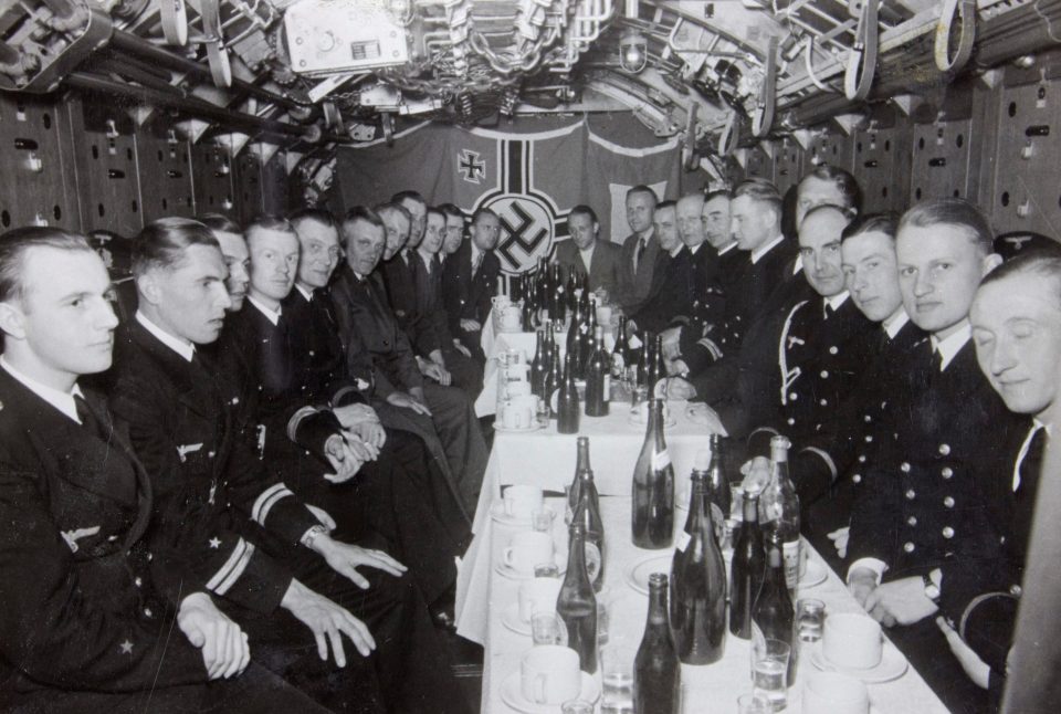  Giant bottles of beer crowd tables as smartly-dressed submarine officers enjoy a formal occasion on board