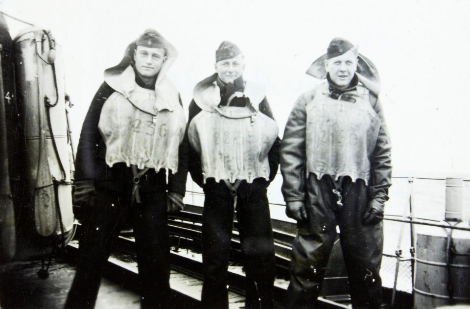  Three crewmen pose for a picture while wearing their life vests