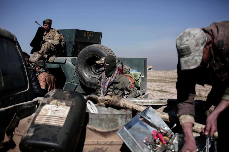  Iraqi forces take a break from fighting on a hillside outside the town of Abu Saif