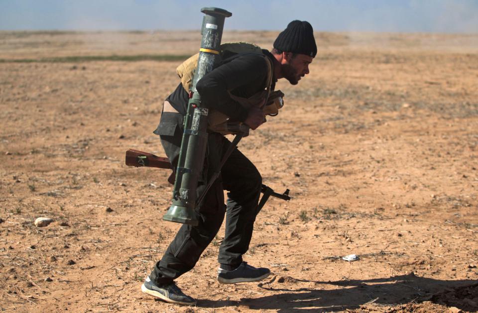  An Iraqi fighter ducks as he advances near the village of Husseinyah