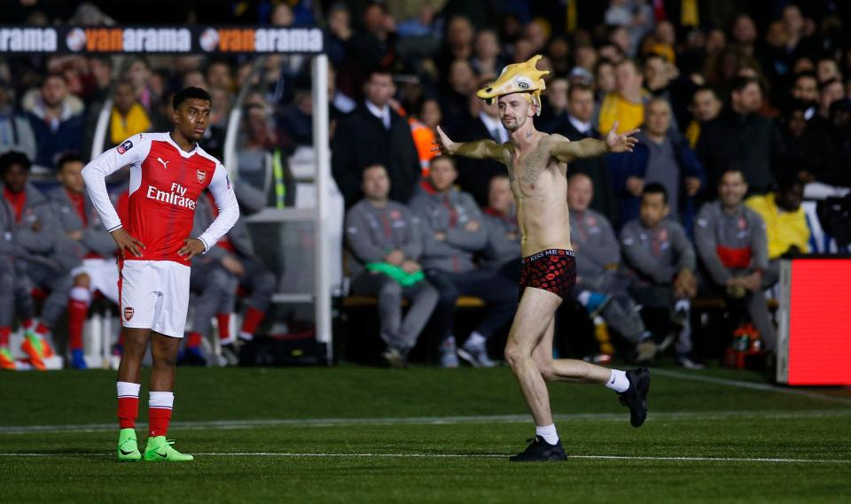 Alex Iwobi watches on as a streaker invades the pitch