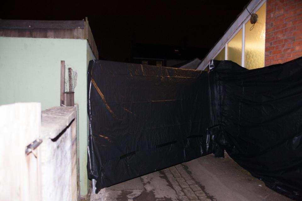  Police have blocked off an alleyway by the houses with black tarpaulin