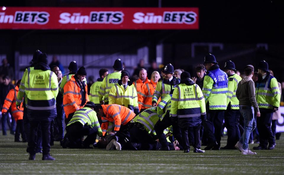  One fan is seen on the floor whilst being surrounded by police and stewards