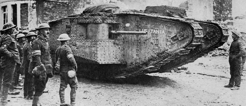  A British Mark I or II male tank, identifiable by long-barrelled naval 6-pounder gun, surrounded by Tommies