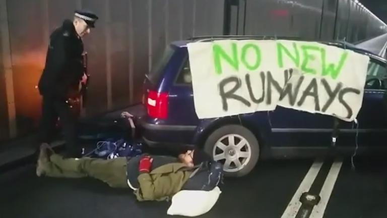 Protesters have chained themselves to a car bearing the banner 'no new runways'