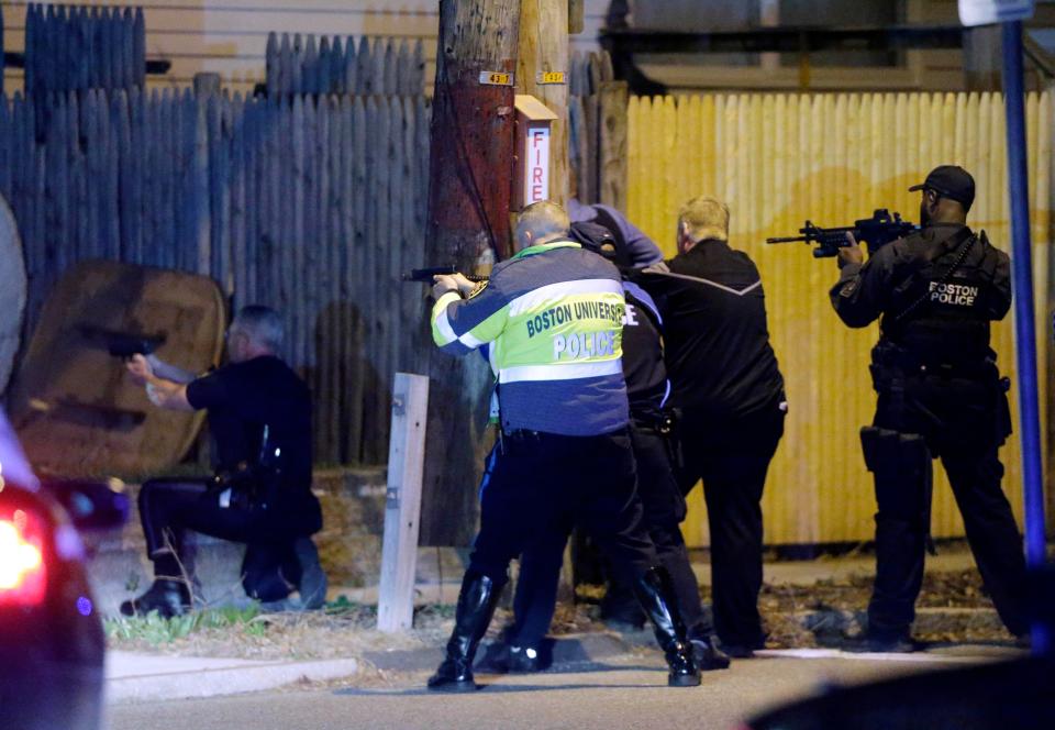 police officers aim their weapons in a Watertown, Mass., neighborhood during a hunt for the Boston Marathon bombing suspects