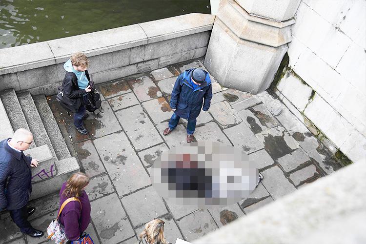  A victim lies at the foot of stairs on Westminster Bridge after this afternoon's attack