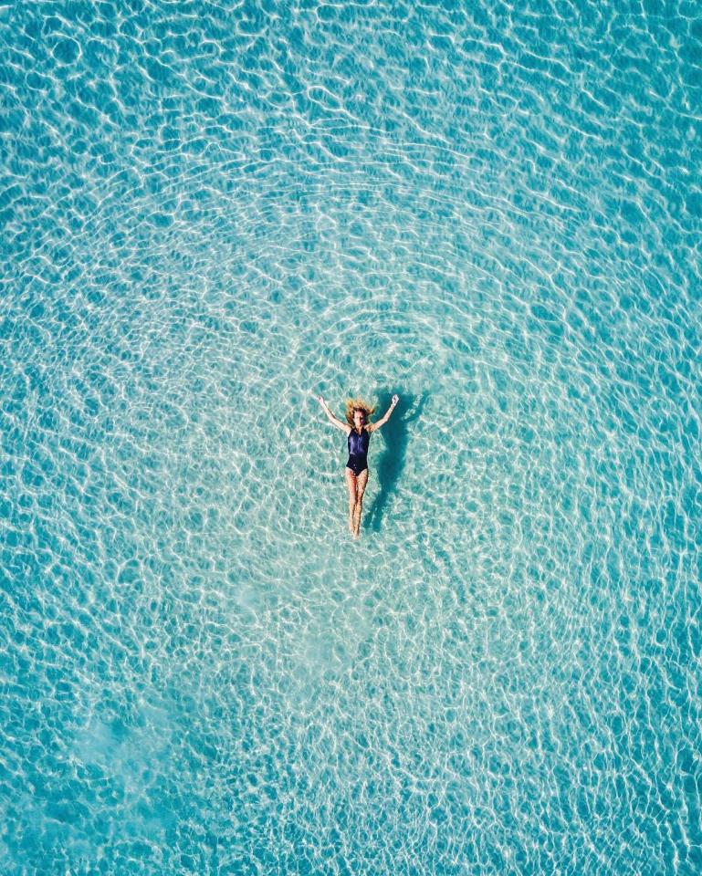  A swimmer appears suspended vertically in the cool blue ocean of Silver Sands in Aldinga Beach when captured from directly above