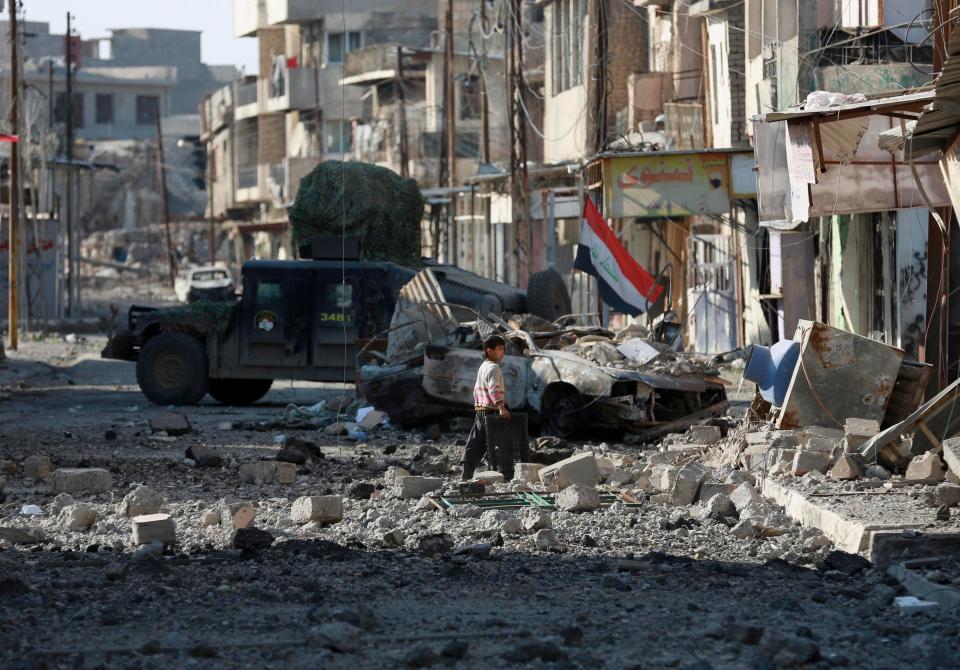  A boy walks among the debris of a damaged neighbourhood in Mosul