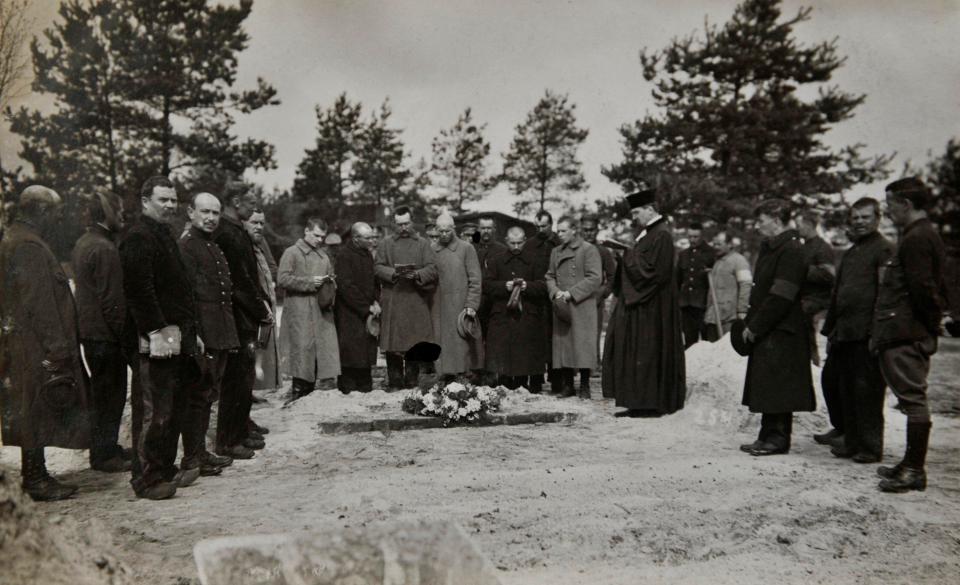  A priest reads from a bible as mourners gather around an open grave