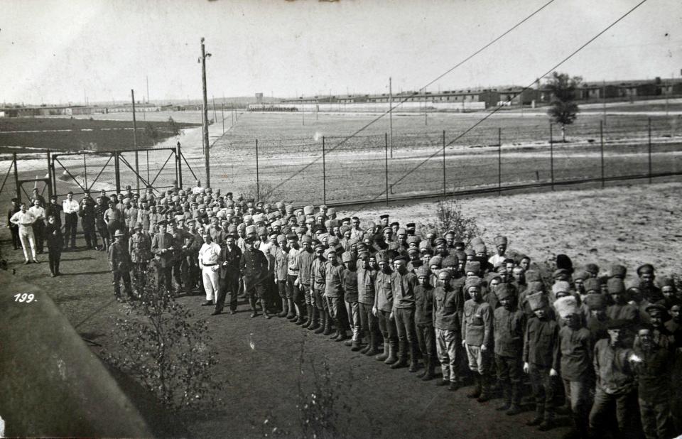  Troops line up neatly in formation in front of high fencing