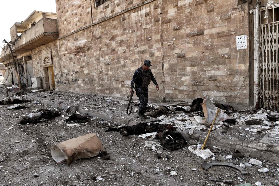  A member of the Iraqi forces walks among bodies of reported jihadists