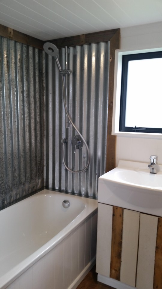 A neat bathroom with shower space that has been lined with corrugated iron 