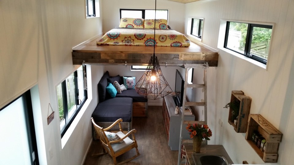 The two-storey property has a cosy living room with a sofa made from wood pallets, with a ladder leading to the double bedroom upstairs