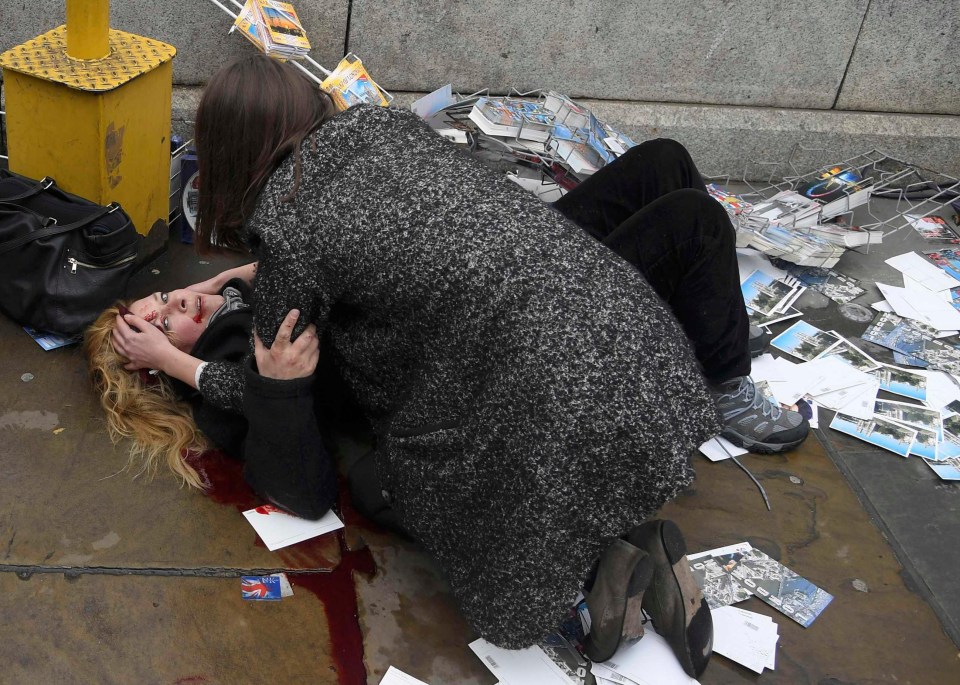 A woman helps a victim of the terror attack which a car plough down pedestrians on Westminster Bridge