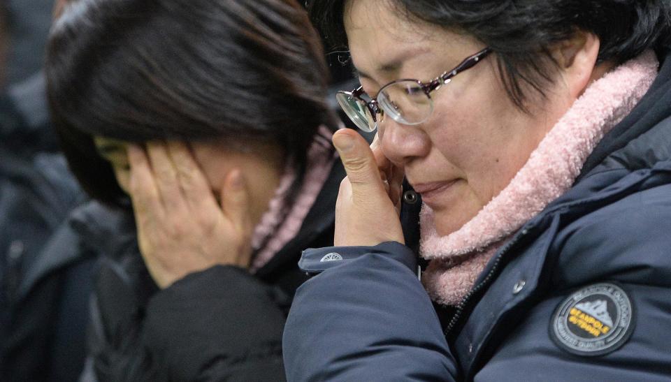  Grieving families watch on as the ship is dragged from the water off Jindo Island, South Korea