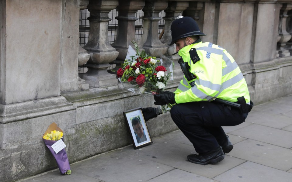  A police officer lays a floral tribute given by a member of the public beside a photo of PC Keith Palmer