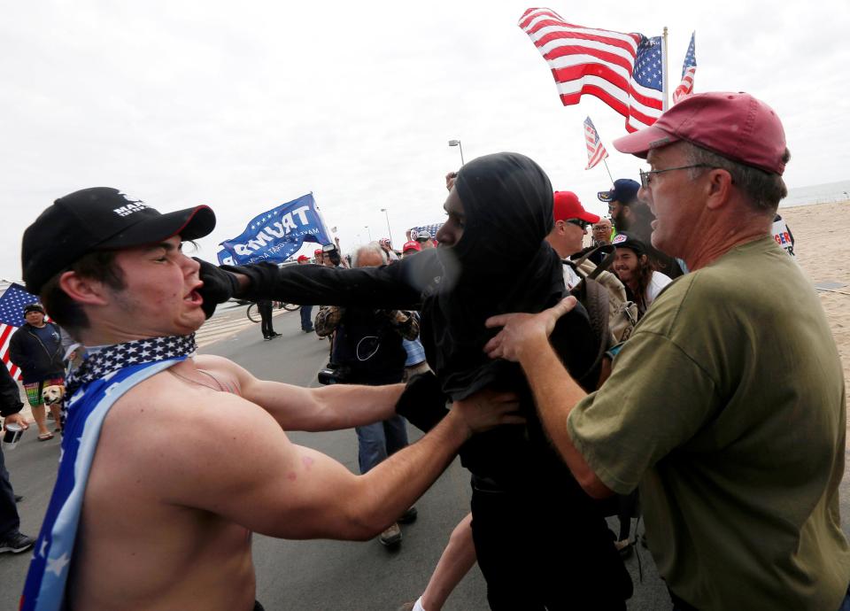 A pro-Trump rally participant is punched in the face by an anti-Trump protester