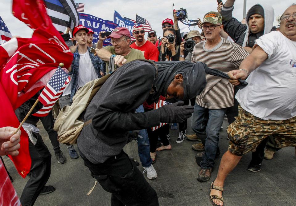 A Trump supporter grabs at the clothing of a black-clad protester yesterday 