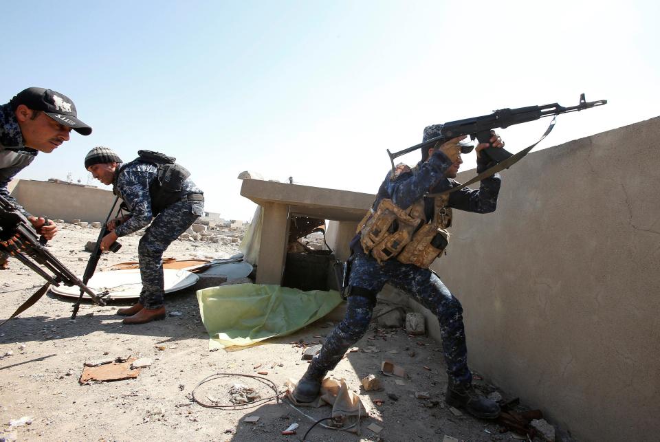  An Iraqi federal policeman fires his rifle at ISIS fighters' positions at Bab al Jadid district in the old city of Mosul on Sunday