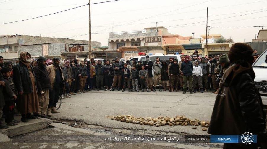  A crowd watches on next to a pile of heavy rocks on the street below