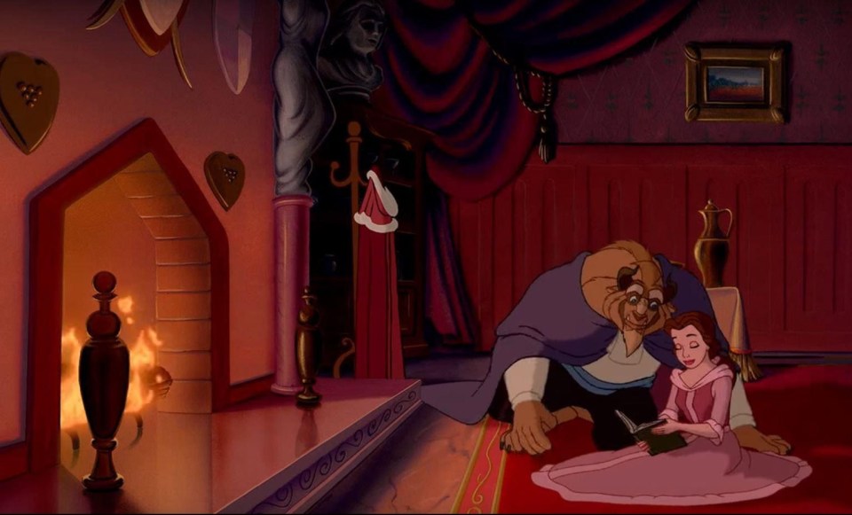 Beauty and the beast snuggle up in front of the fire in the cartoon version of the film 