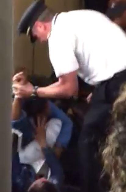  The pilot grabs a woman's arm as the pair wrestle on the ground