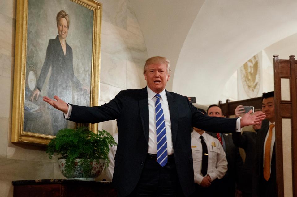 Trump standing below a painting of the former First Lady, Hillary Clinton, who he defeated during the presidential election