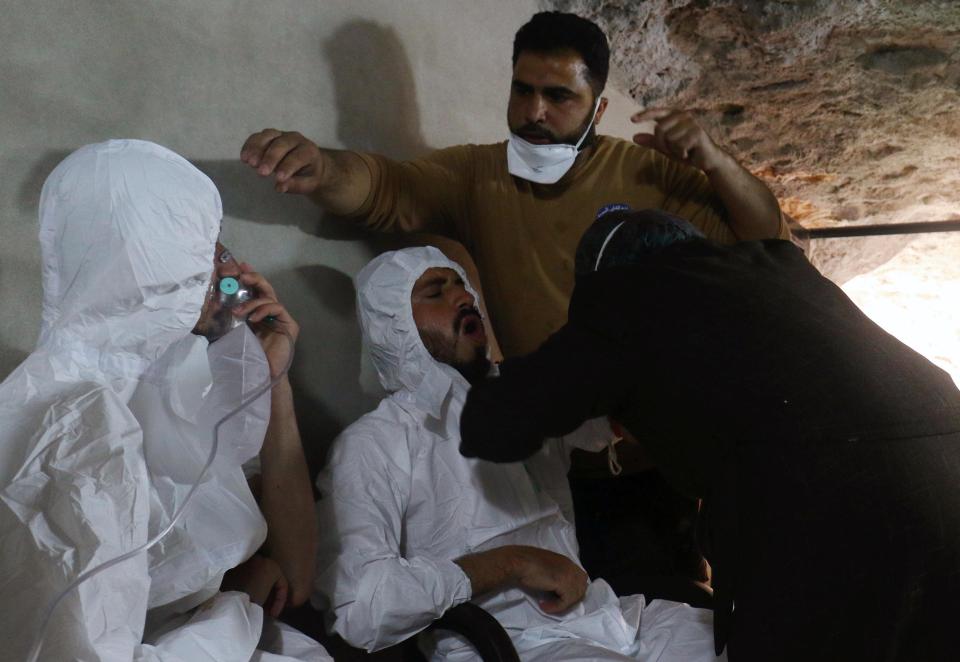  Men in chemical suits are given oxygen after the suspected chemical attack