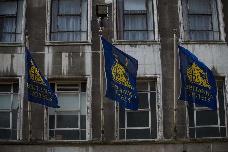 Three flags next to the dirty frontage of the Britannia Hotel on New Street, Birmingham