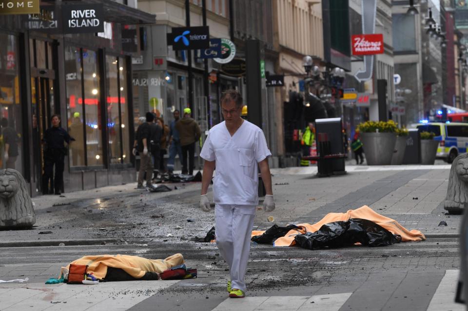  A doctor walks through the carnage as bodies lay on the floor covered with blankets